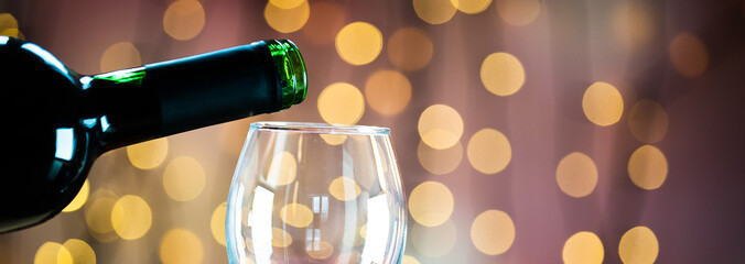  Pouring red wine into the glass. Golden bokeh background.