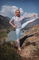 young fitness woman practice yoga at mountain peak cliff edge