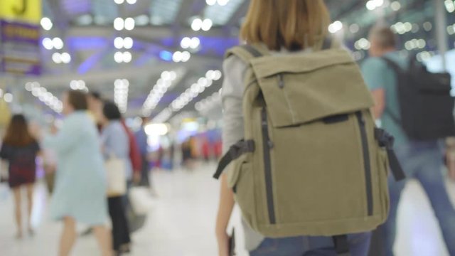 Young Asian backpacker woman tourist walking in terminal hall while going to boarding flight at the departure gate in international airport. Lifestyle backpack tourist travel holiday concept.