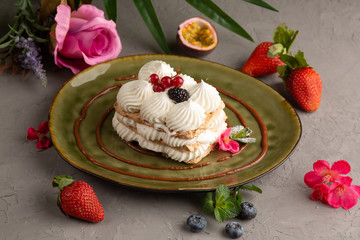 Cake with whipped cream and berries on a green plate