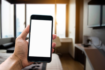A man hand holding smart phone device in the bright office room interior.