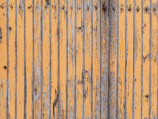 peeling orange paint on vertical wooden planks of an abandoned trailer