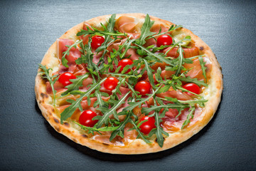 Pizza with cherry tomatoes and black olives and arugula