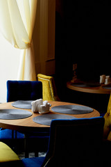 Empty wooden table surrounded by four purple velvet armchairs in modern restaurant