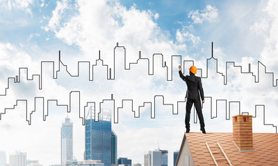 Man architect draw silhouette of modern city on blue sky. Mixed media