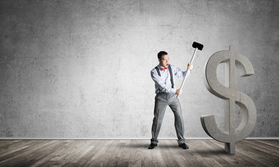 Obraz premium Determined banker man in empty concrete room breaking dollar figure