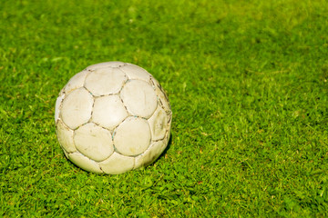 Old shabby soccer ball on a green lawn