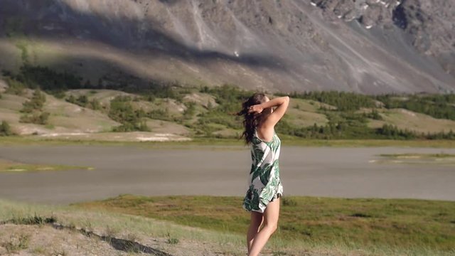 young woman dancing and running against the backdrop of the mountains in a dress