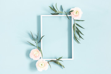 Flowers composition. White flowers, eucalyptus leaves, photo frame on pastel blue background. Flat...