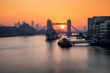 Sonnenaufgang hinter der Tower Bridge in London mit Sicht auf die Wolkenkratzer von Canary Wharf
