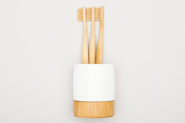 natural bamboo toothbrushes in stand on grey background