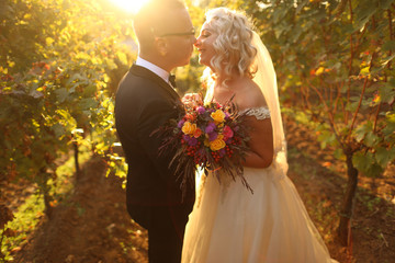 Handsome groom and bride posing outdoor, bride holding bouquet of flowers in hands