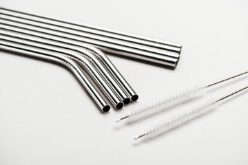 close up view of of stainless steel straws and cleaning brushes on grey