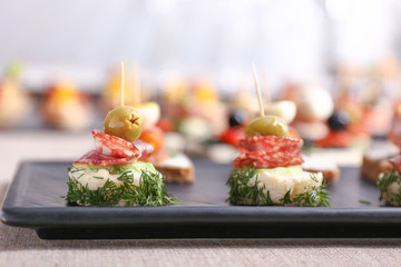 Plate with tasty canapes on table