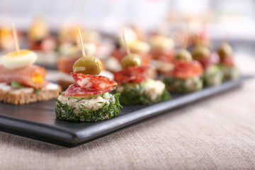 Plate with tasty canapes on table