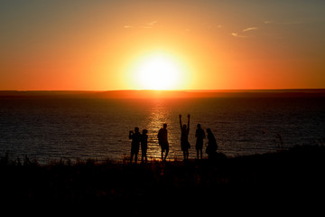 Fototapeta premium Silhouettes of a group of people watching the sunset over the Volga river