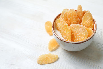 Bowl with tasty dried ginger with sugar on white wooden table