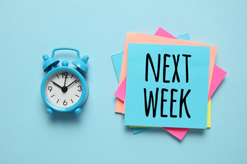 Blue alarm clock and paper reminder, next week. Time management, priorities, efficiency, control...