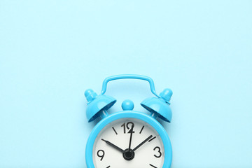 Blue alarm clock isolated on blue background.