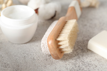 Massage brush with cosmetics on grey background