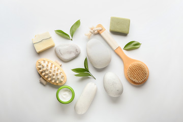 Massage brushes with cosmetics and spa stones on white background