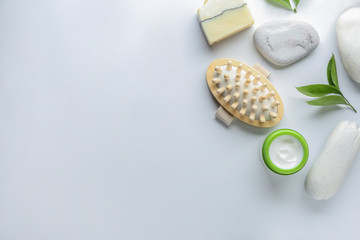 Massage brush with cosmetics and spa stones on white background