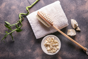 Massage brush with towel and soap on grey background