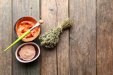 Bowls with cosmetic clay on wooden table
