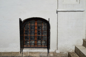 Old window with metal shutters against a white brick wall