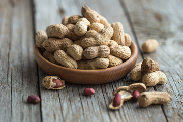 Close up view of shelled peanuts in wooden background.