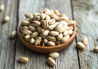 Unpeeled pistachios in a wooden cedar plate