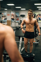 Fototapeta na wymiar Muscle guy posing in front of mirror