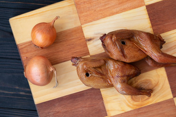 dish of smoked quail on wooden board