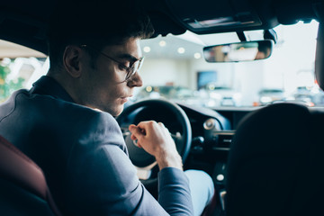 selective focus of successful man in glasses sitting in automobile