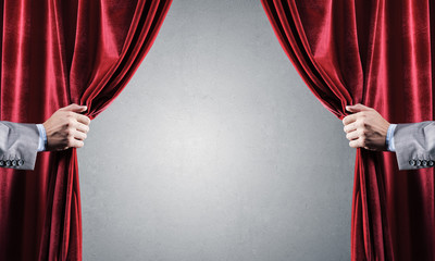 Concrete wall behind drapery curtain and hand opening it
