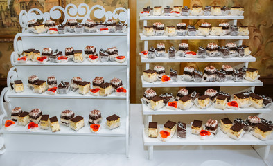 Delicious candy bar at the wedding reception. Chocolate cakes and muffins.Sweet red hearts. Desserts for guests.