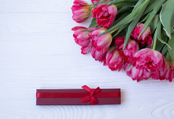 Pink tulip flowers bouquet and gift box over wooden background. Women day or birthday celebration concept