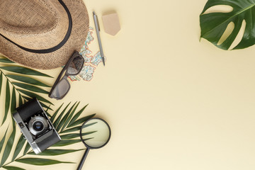 sunglasses hat magnifying glass camera pen notes palm leaf monstera top view with copy space for your text. flat lay. 