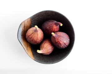 Organic figs in a bowl on white table