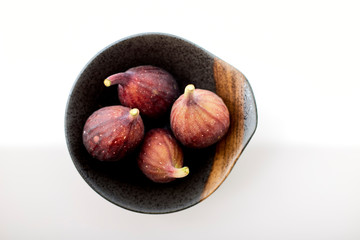 Organic figs in a bowl on white table