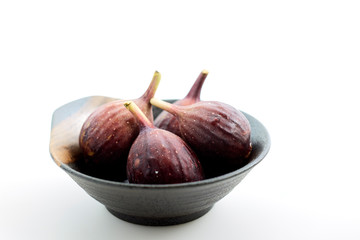 Organic figs in a bowl on white table