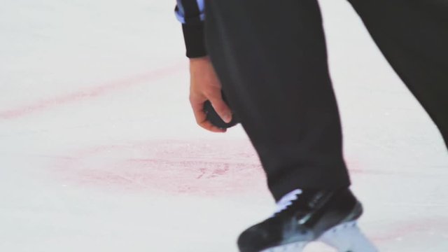 closeup hockey arbiter takes away black puck at competition