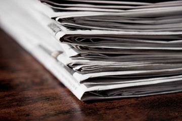pile of newspapers or papers on wooden table - print media news