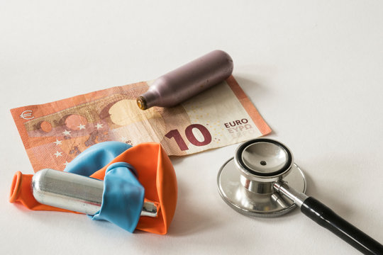 close up metal bulb for laughing gas, party drugs, with balloons., money and stethoscope