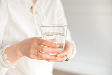 Glass of clean mineral water in woman's hands. Concept of environment protection, healthy drink.
