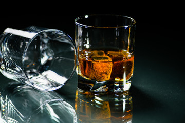 glasses of whiskey on a glass table with a lemon isolated on a black background, special stones for whiskey. glass objects