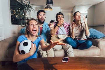 Happy friends or football fans watching soccer on tv and celebrating victory at home.Friendship, sports and entertainment concept. - Powered by Adobe