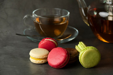 Dessert macaroons on a plate with a kettle of tea