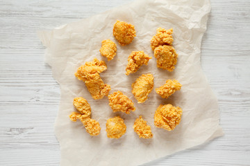 Chicken bites on baking sheet over white wooden background, top view. Flat lay, overhead, from above.