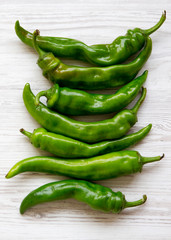 Green chili peppers on white wooden background, top view. Flat lay, from above, overhead. Copy space.